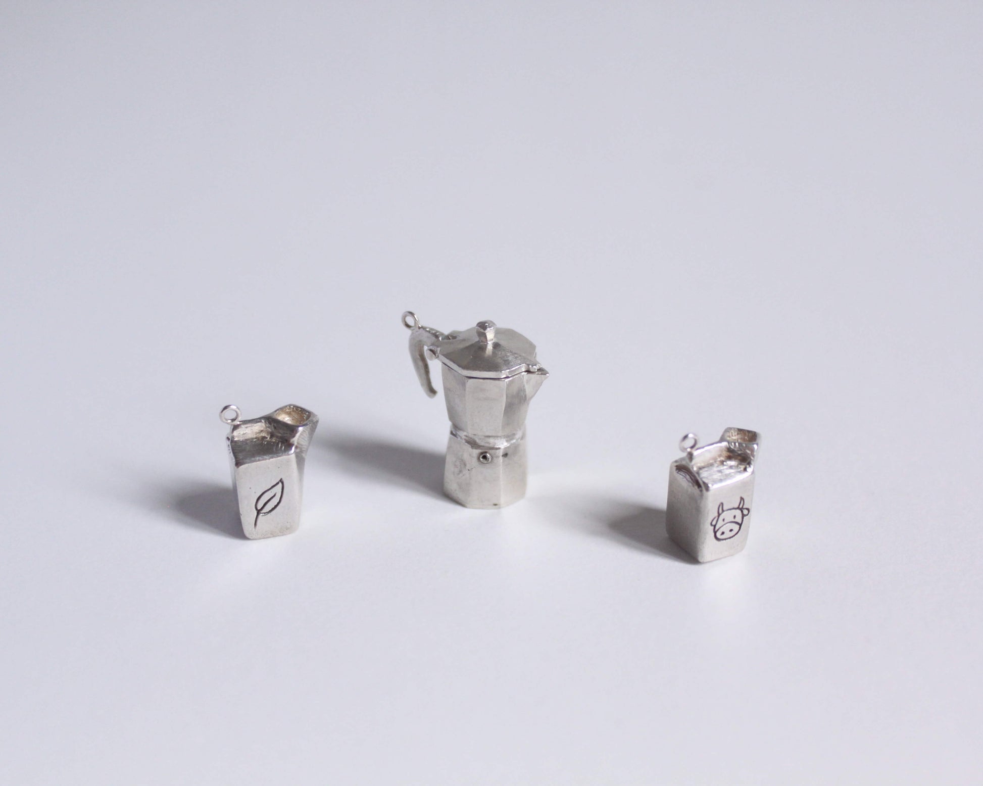 série de pendentifs en argent massif symbolisant des briques de lait et une cafetière italienne