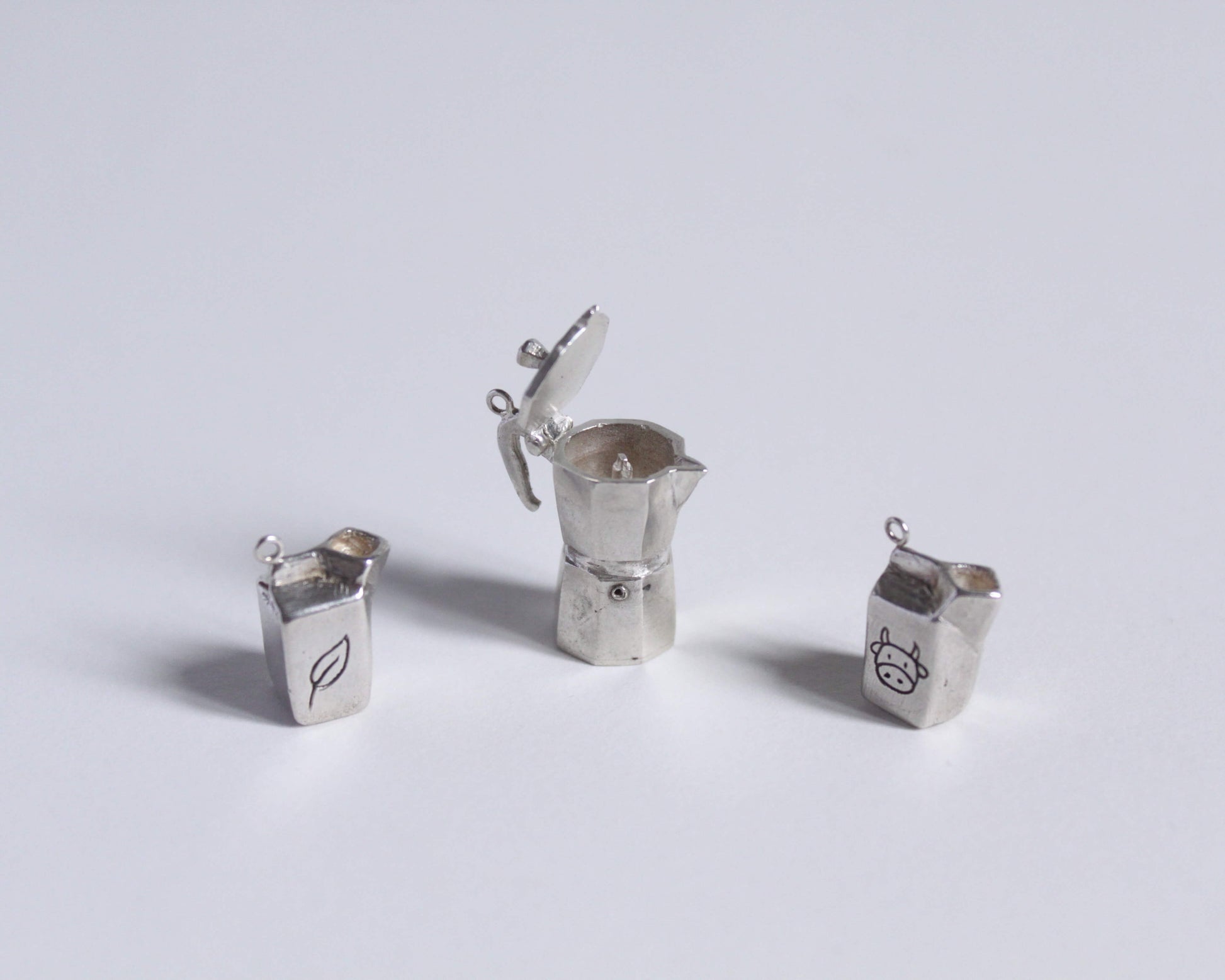 des pendentifs en argent représentant des briques de lait et une cafetière italienne