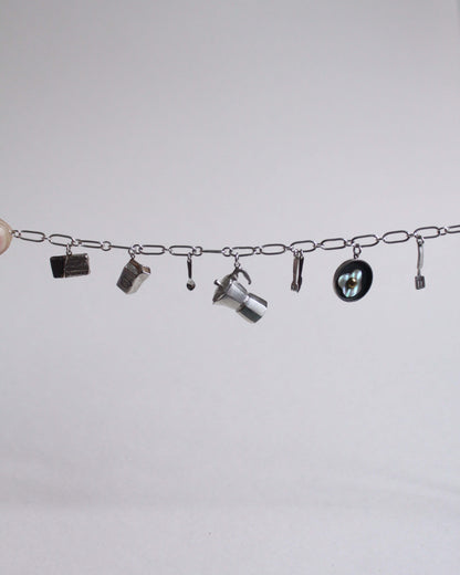 une chaine à laquelle sont accrochés différents pendentifs en argent sur le thème du petit déjeuner