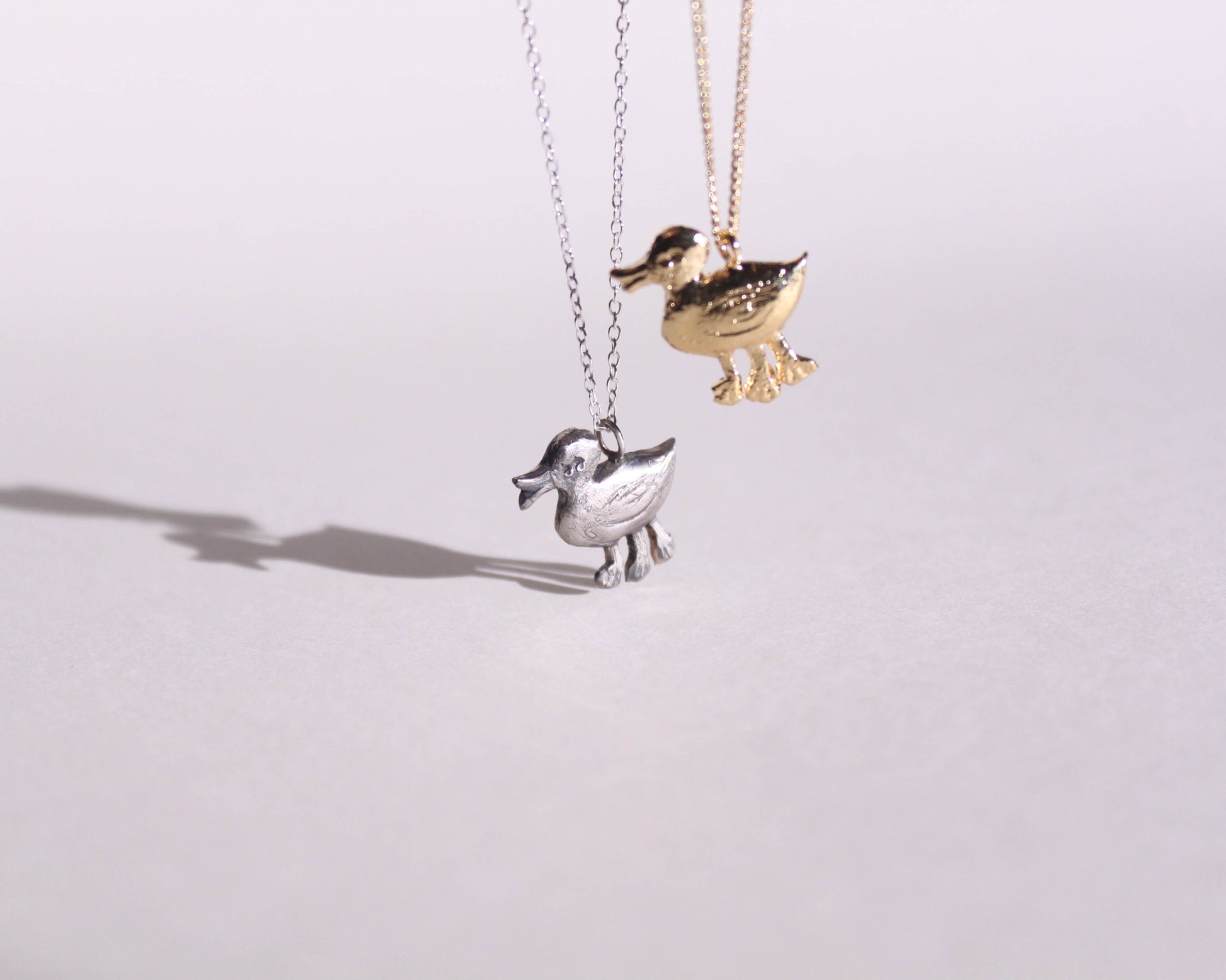 pendentifs en argent massif et en laiton plaqué or représentant des canards disposant de trois pattes