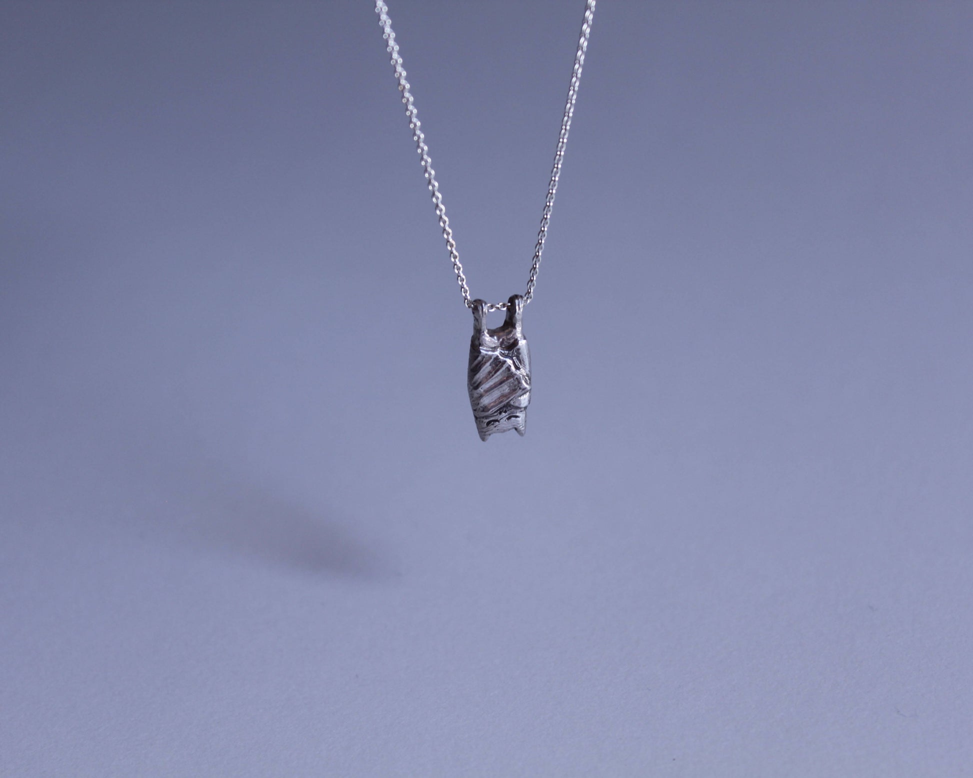 pendentif en argent représentant une chauve souris endormie avec la tête en bas