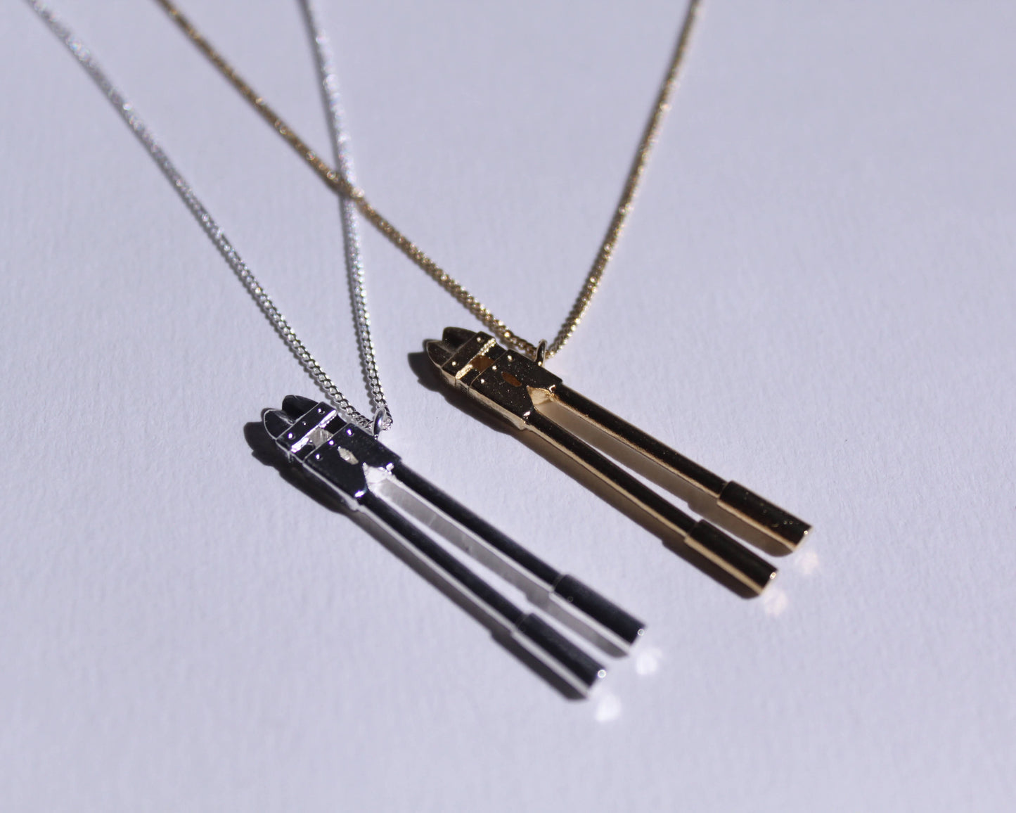 deux pendentifs en laiton plaqué or et en argent massif en forme de coupes boulons