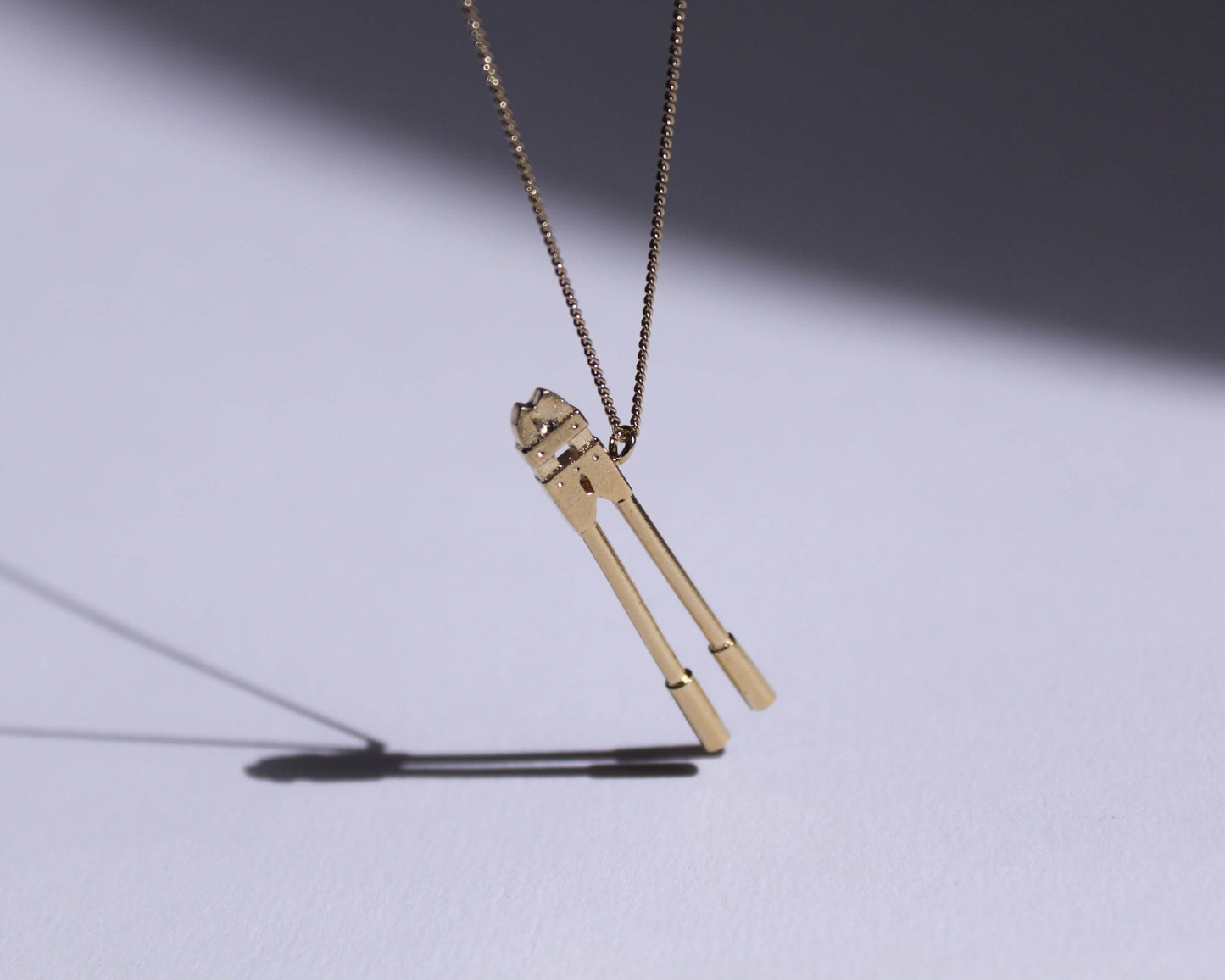 pendentif en laiton plaqué or représentant un coupe boulons