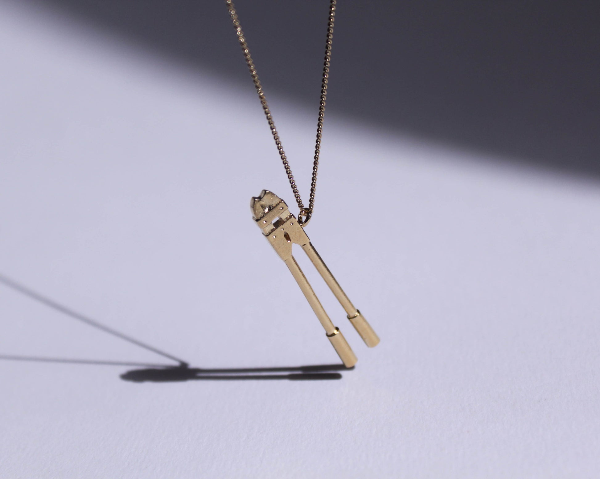 pendentif en laiton plaqué or représentant un coupe boulons