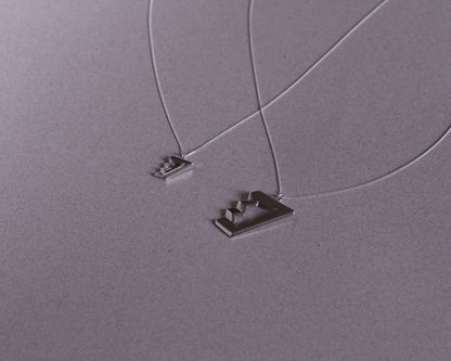 deux colliers avec des pendentifs en argent massif symbolisant des escaliers de penrose
