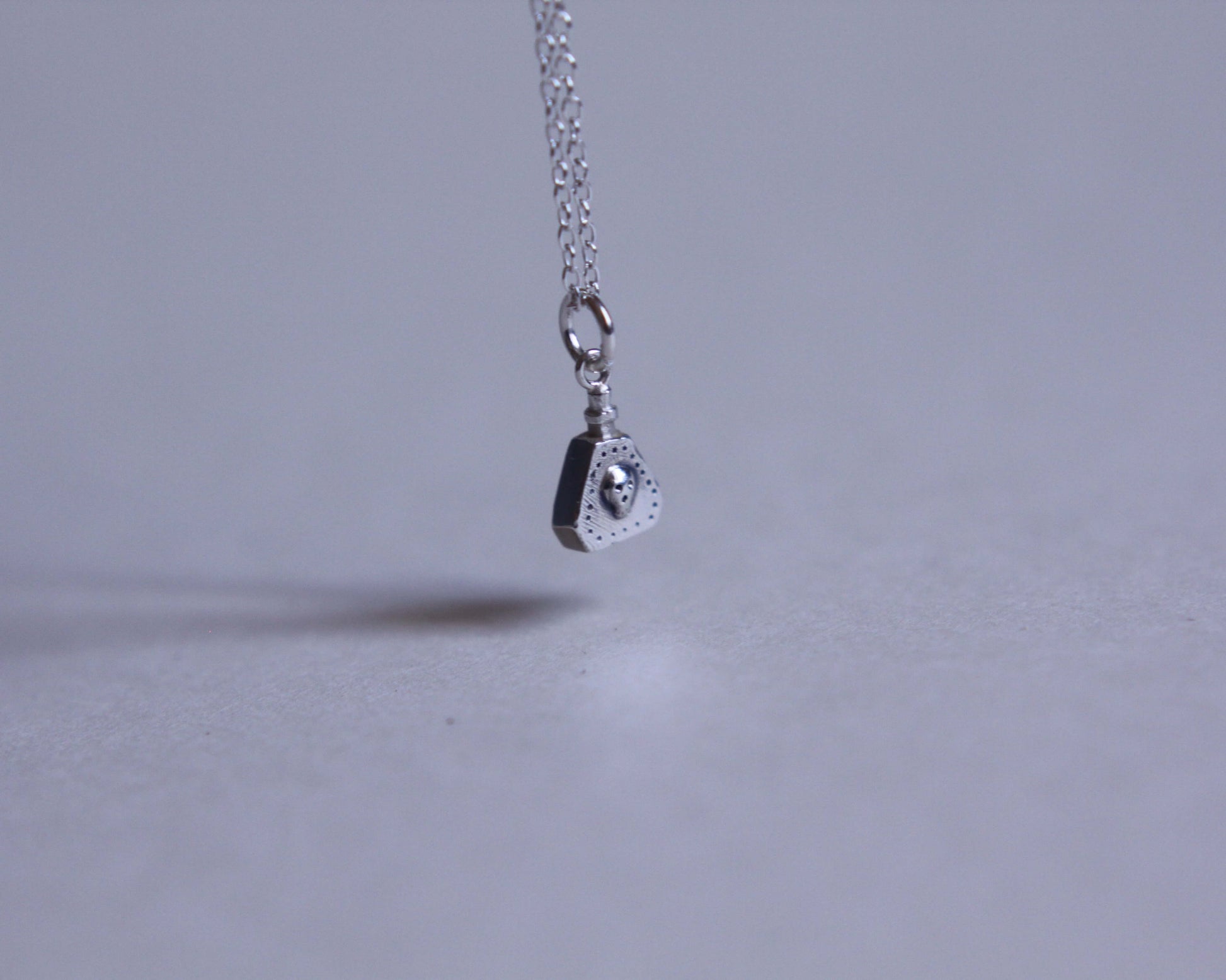 pendentif en argent massif en forme de fiole de poison au bout d'une chaine