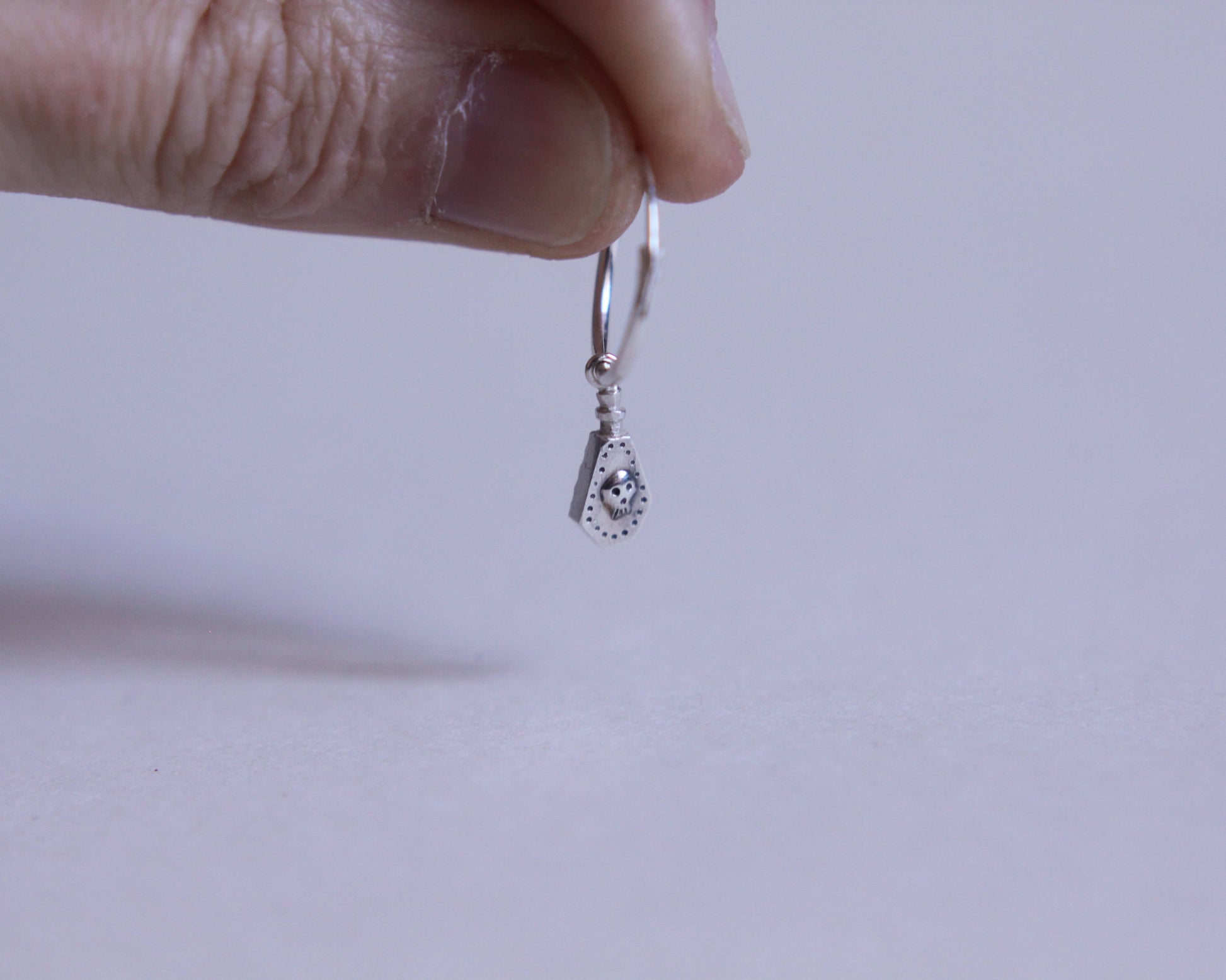 boucle d'oreille en argent massif représentant une fiole de poison avec un crâne dessus