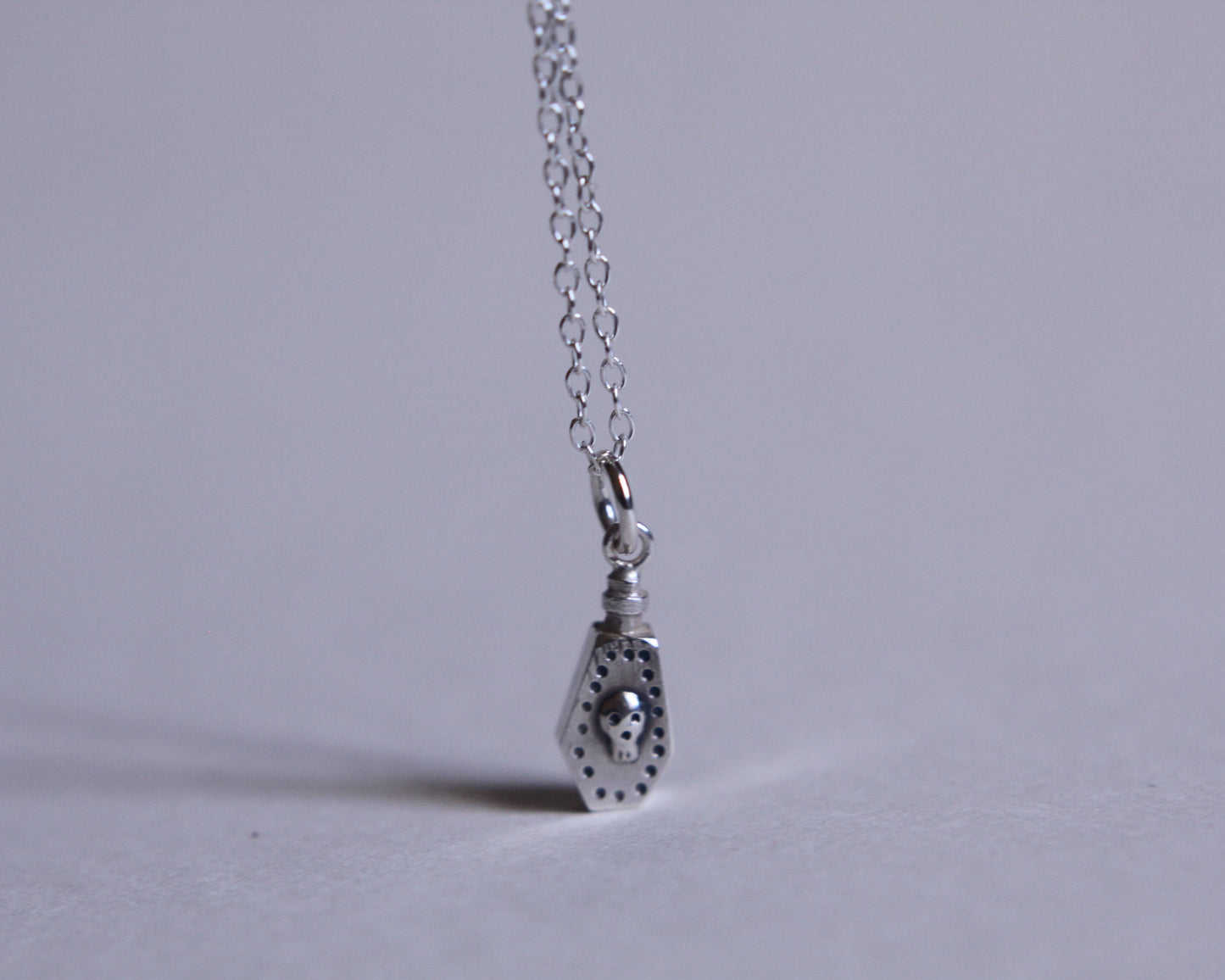 pendentif en argent au bout d'une chaine représentant une fiole de poison