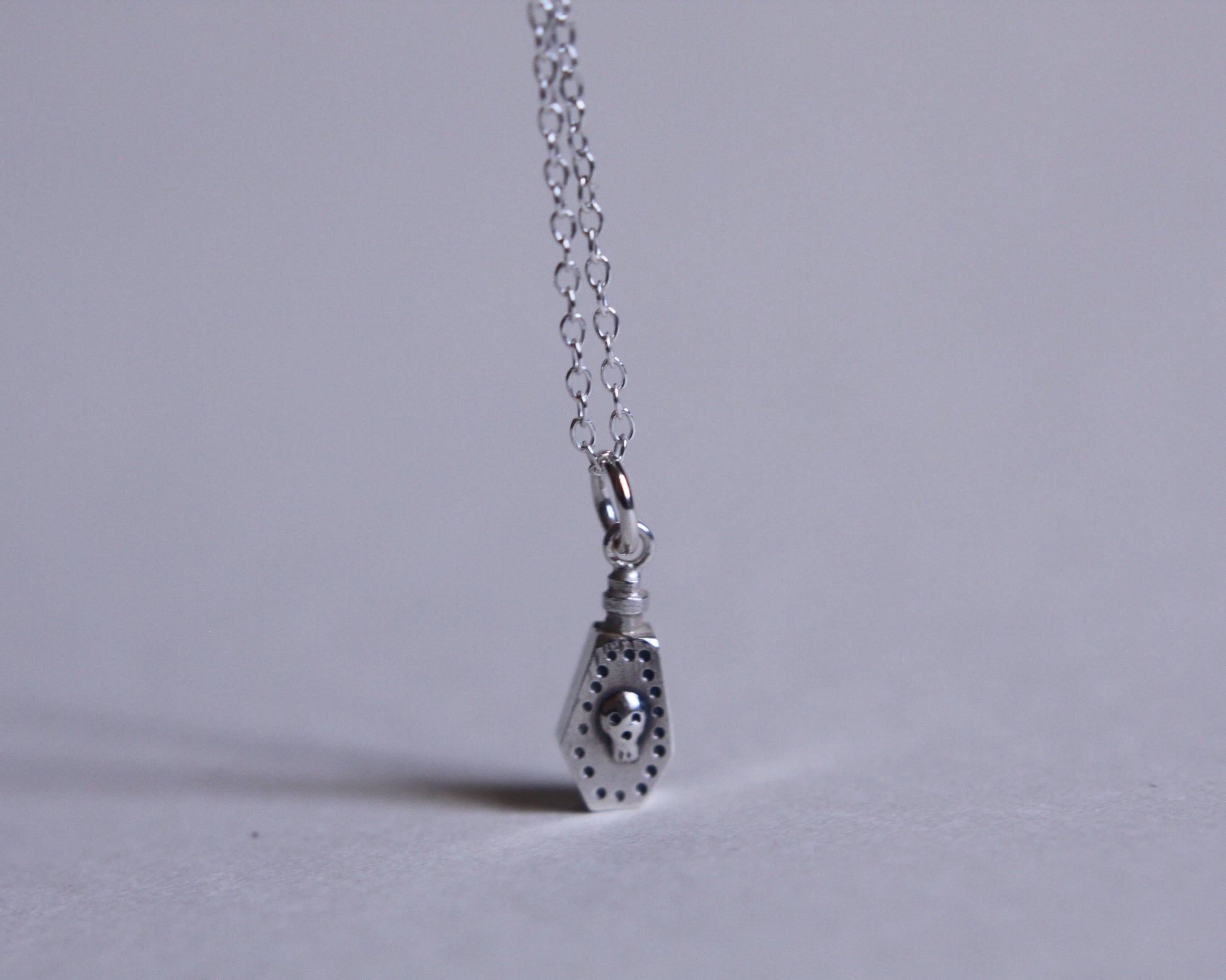 pendentif en argent au bout d'une chaine représentant une fiole de poison