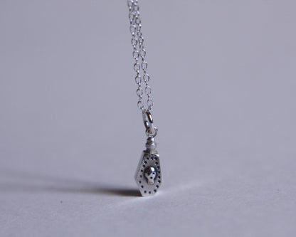 pendentif en argent au bout d'une chaine représentant une fiole de poison