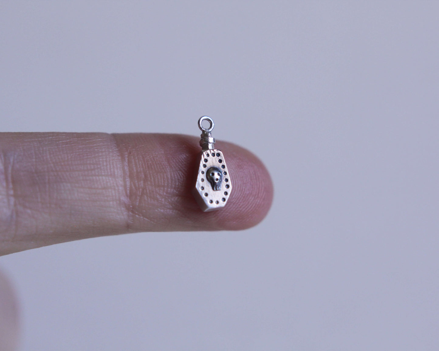 pendentif en argent en forme de fiole de poison avec un crâne dessus