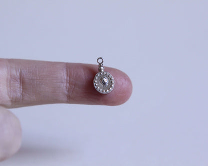 zoom sur un pendentif rond en forme de fiole de poison avec un crâne dessus