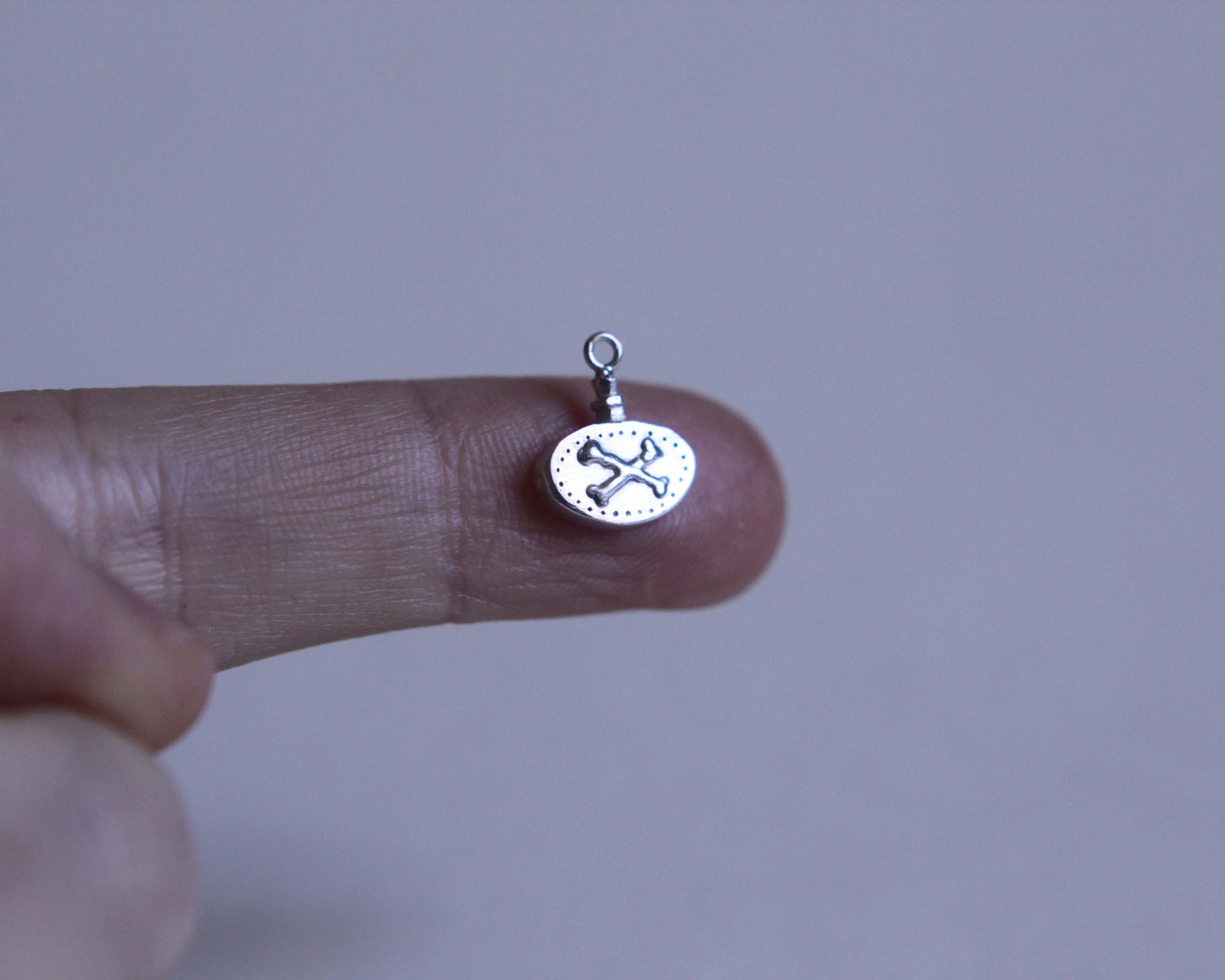 pendentif ovale en argent massif représentant une fiole poison avec des os dessus