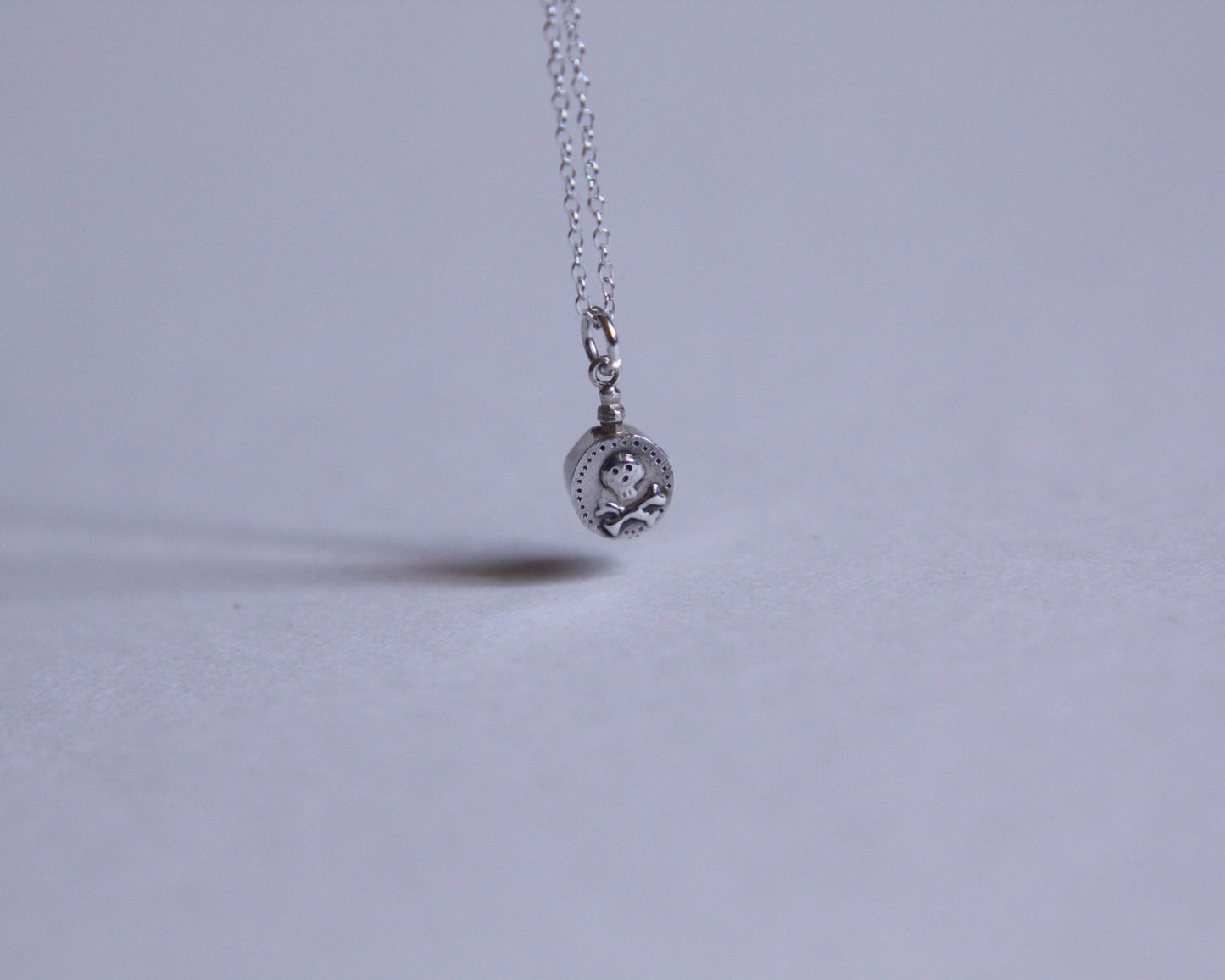 petit pendentif en argent en forme de fiole de poison décoré d'une tête de mort