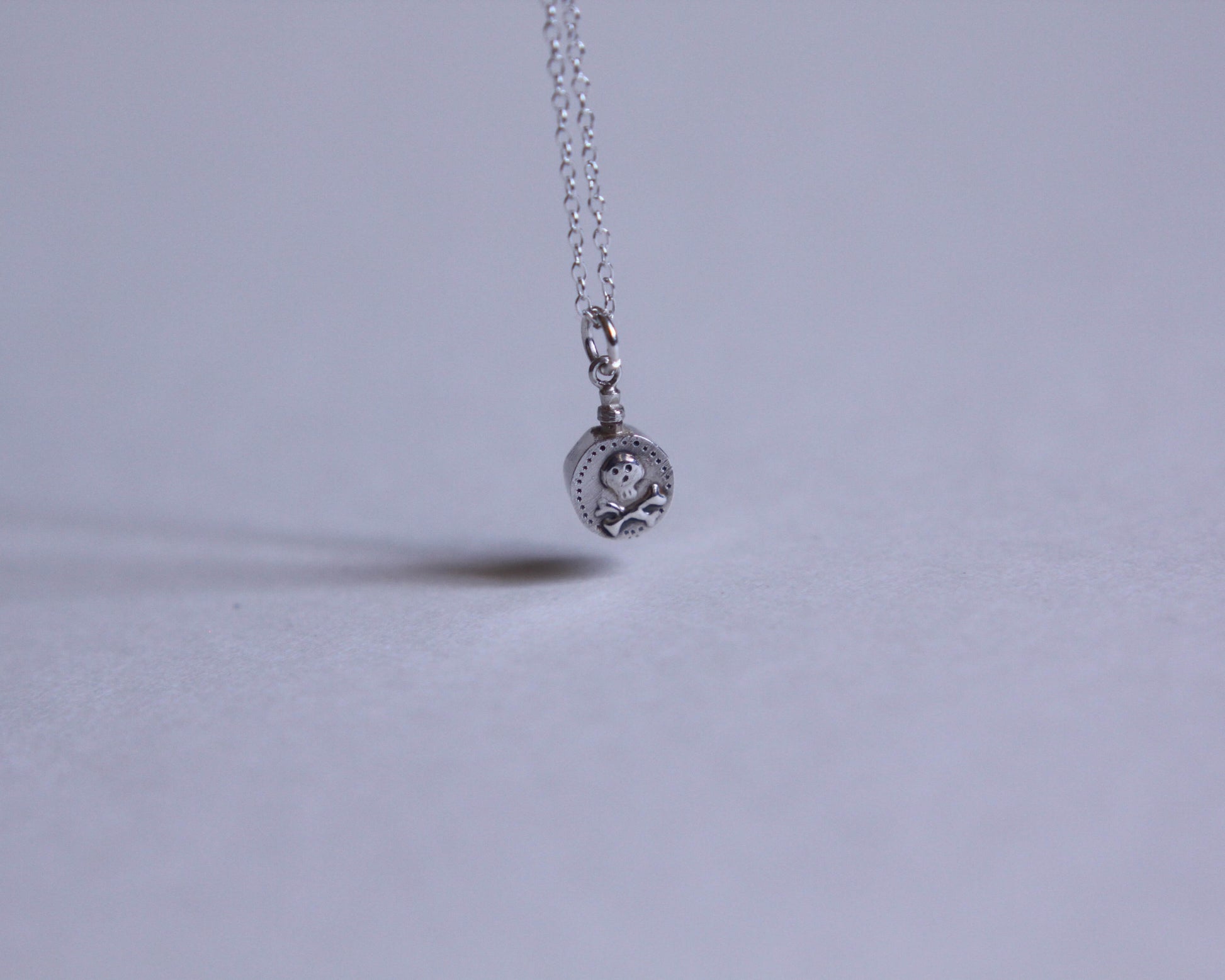 petit pendentif en argent en forme de fiole de poison décoré d'une tête de mort