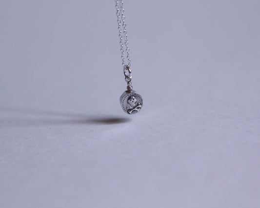 petit pendentif en argent en forme de fiole de poison décoré d'une tête de mort