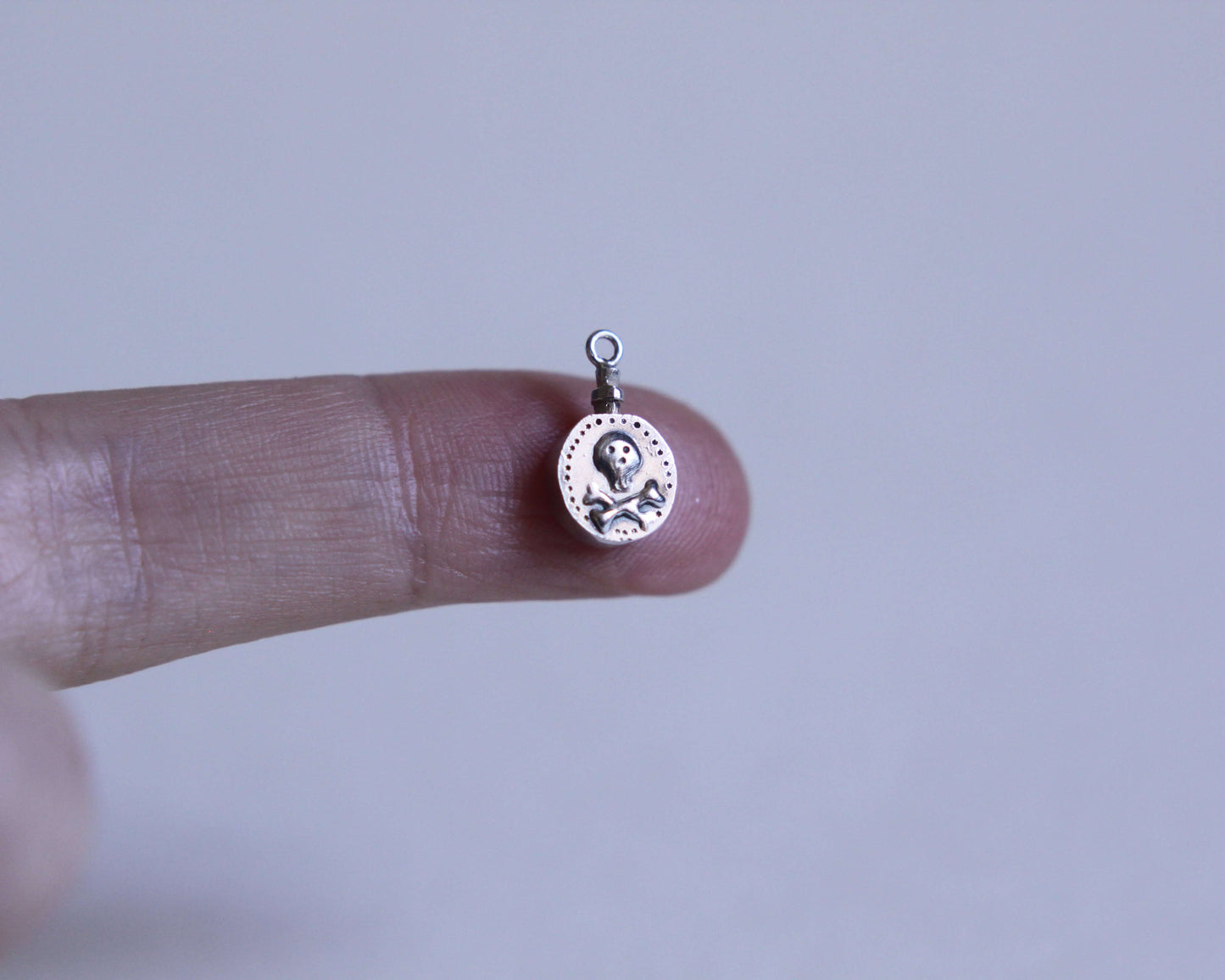 pendentif en forme de fiole de poison en argent avec une tête de mort dessus