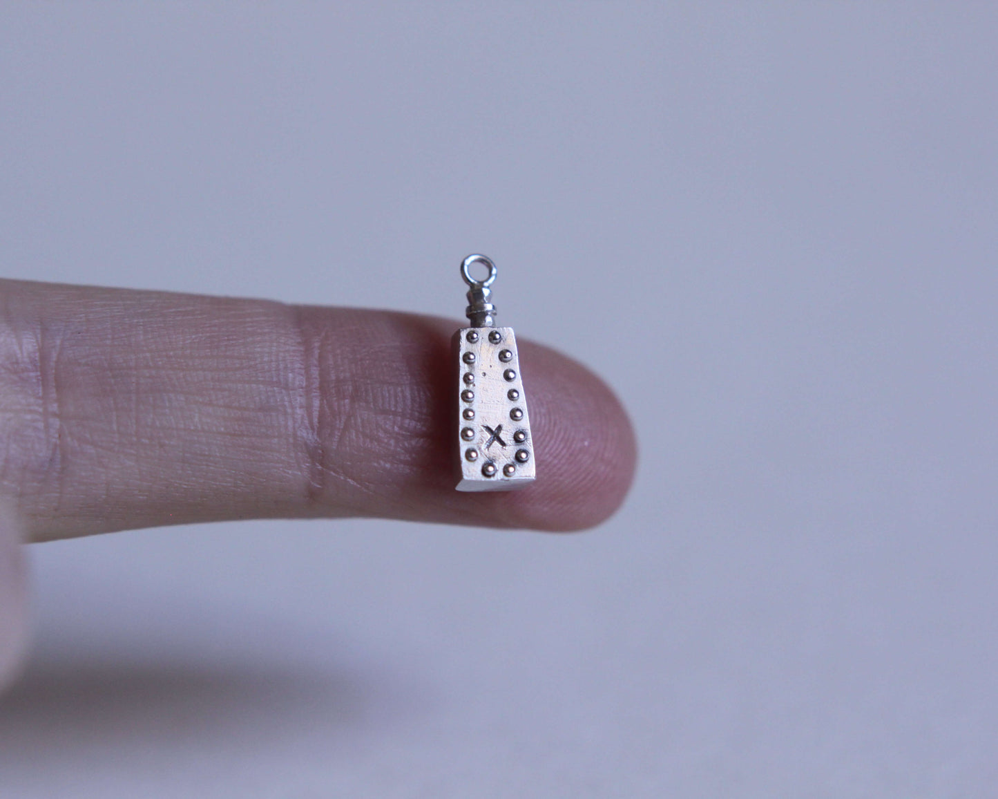 pendentif en forme de fiole de poison en argent avec une petite croix dessus