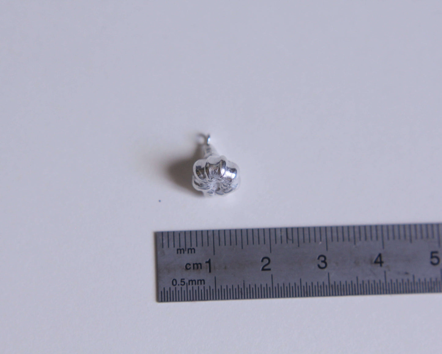 pendentif en argent massif représentant une gousse d'ail avec une règle à coté