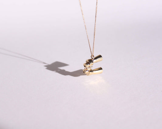 pendentif en laiton plaqué or symbolisant une paire de jumelles, suspendu au bout d'une chaine