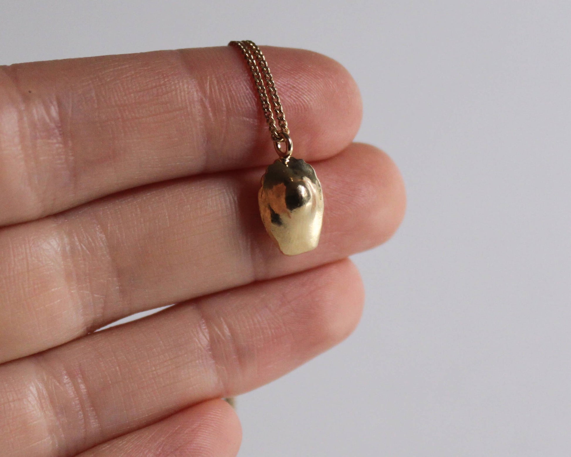 zoom sur un collier avec un pendentif en laiton plaqué or en forme de madeleine