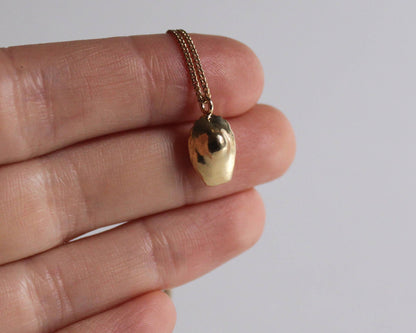 zoom sur un collier avec un pendentif en laiton plaqué or en forme de madeleine