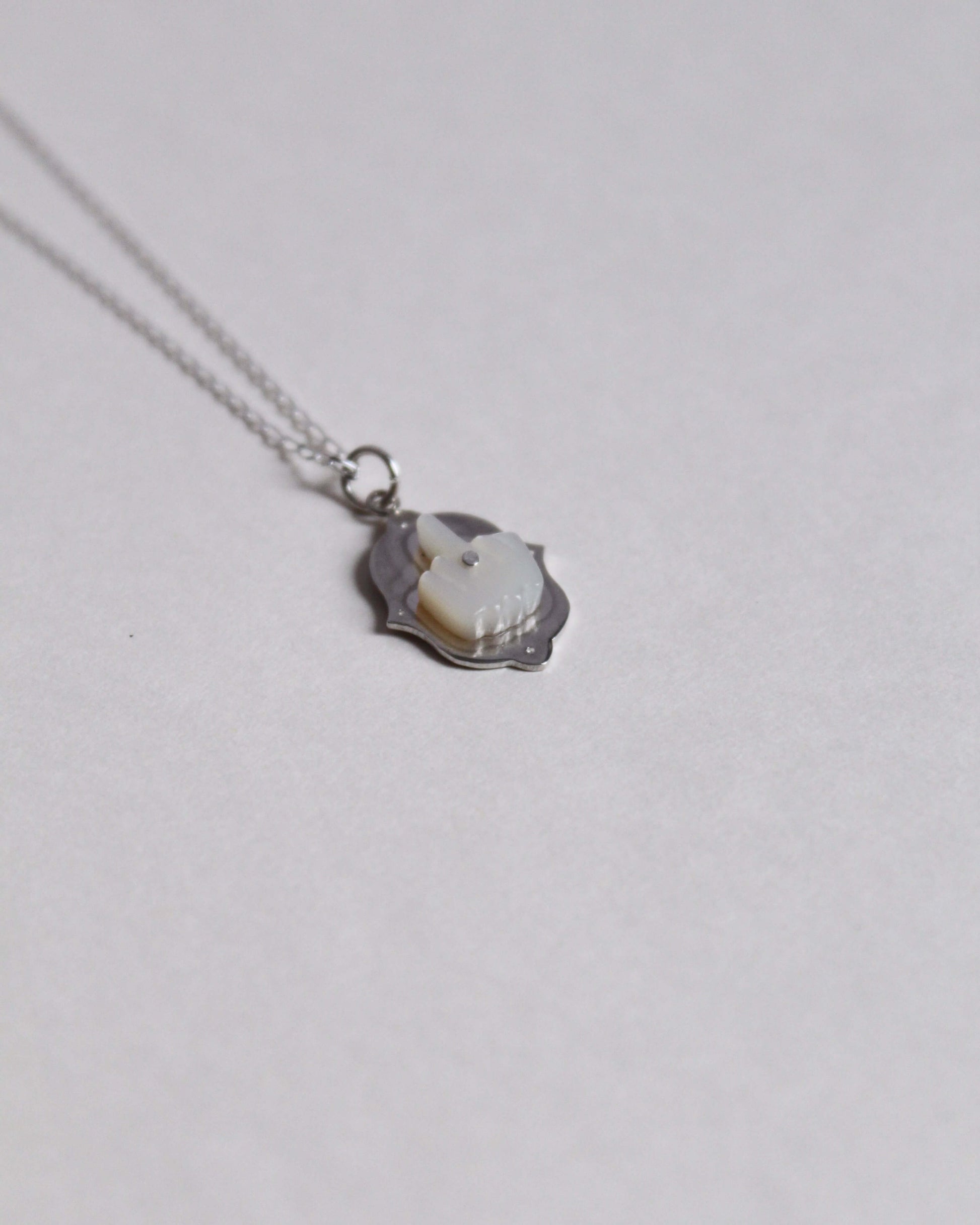 collier pendentif en forme de doigt d'honneur en nacre sculptée