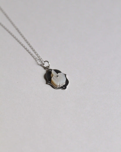 pendentif représentant un doigt d'honneur en nacre sculptée sur argent