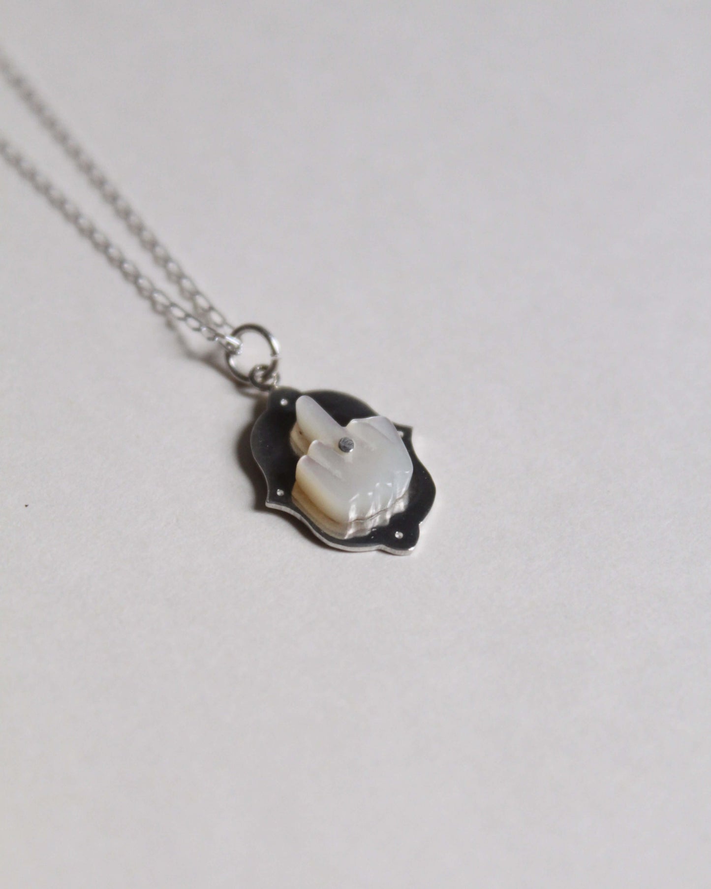 pendentif en nacre et en argent symbolisant un doigt d'honneur