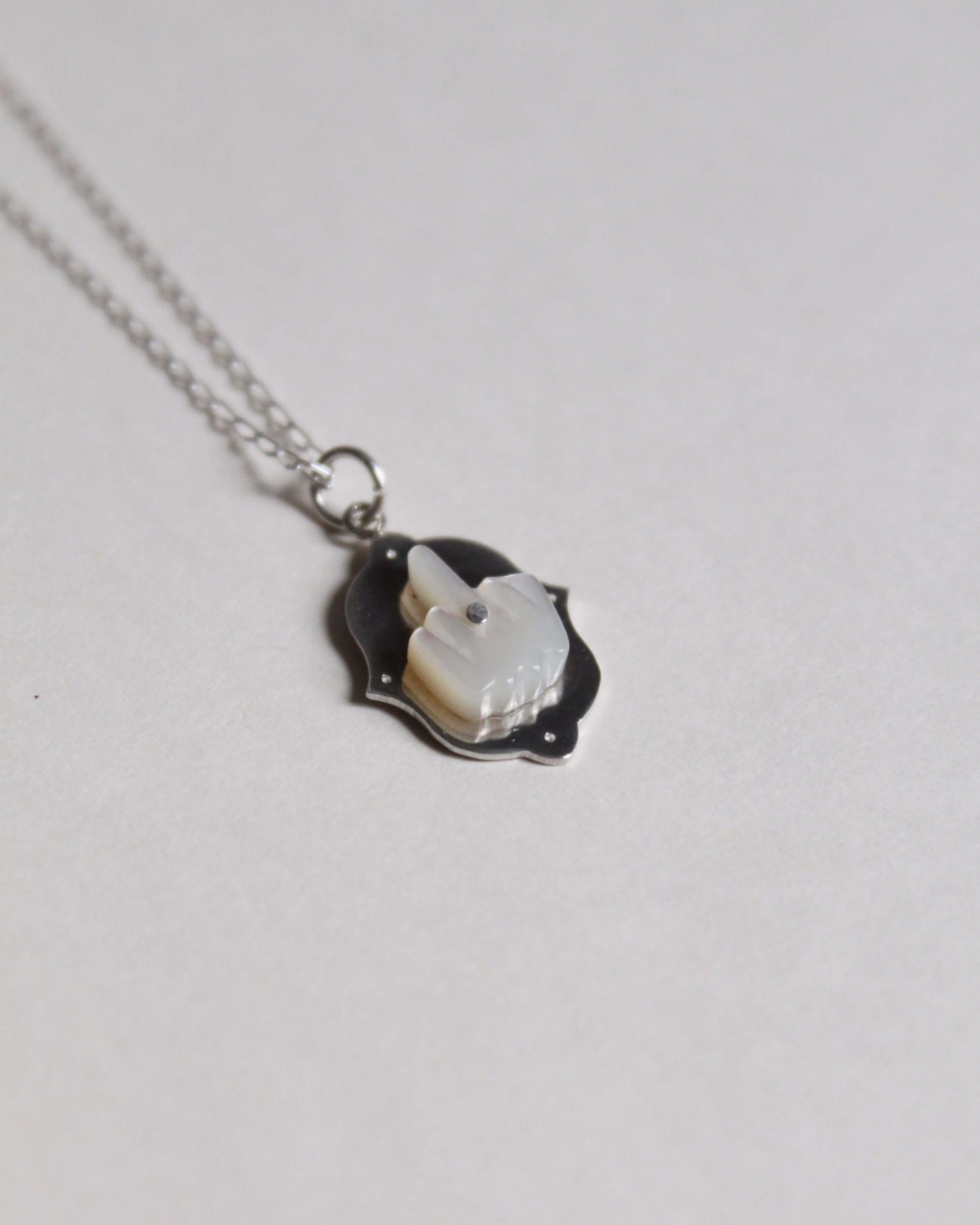 pendentif en nacre et en argent symbolisant un doigt d'honneur