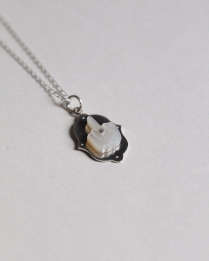 pendentif en nacre et en argent symbolisant un doigt d'honneur