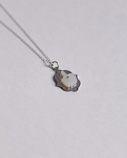 pendentif en argent surmonté d'un doigt d'honneur en nacre sculptée au bout d'une chaine