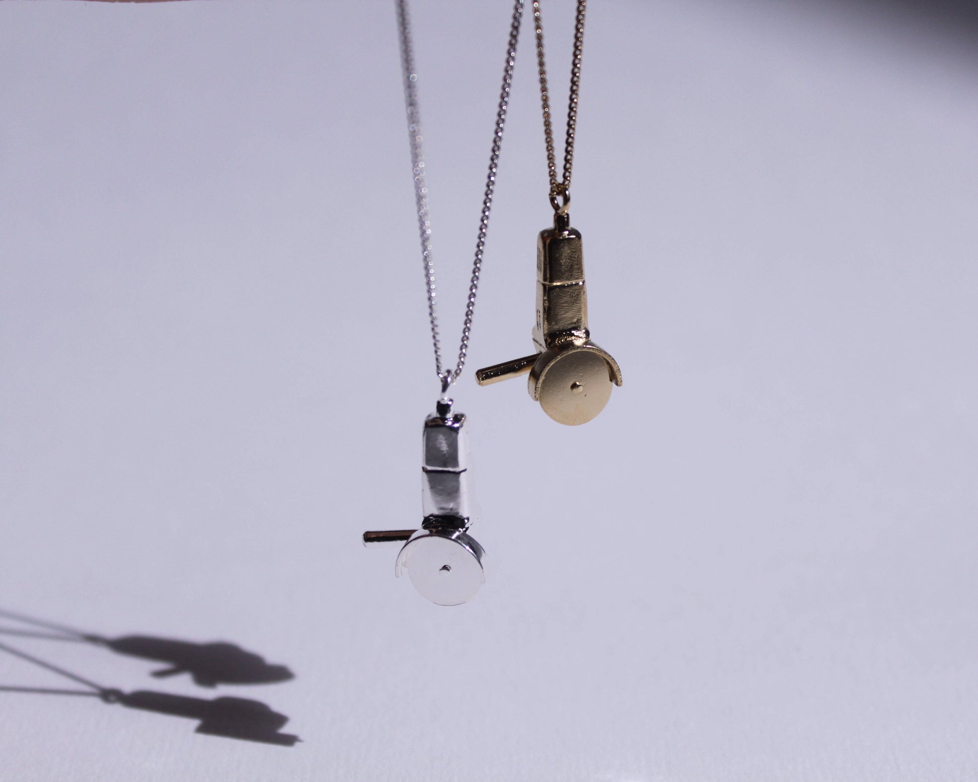 deux pendentifs en laiton plaqué or et en argent massif en forme de disqueuses