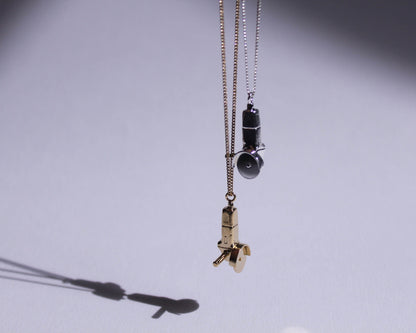 des pendentifs en argent massif et en laiton plaqué or représentant des meuleuses avec la lame qui tourne