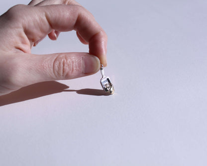 pendentif en argent symbolisant un poêlon à raclette avec du fromage qui coule