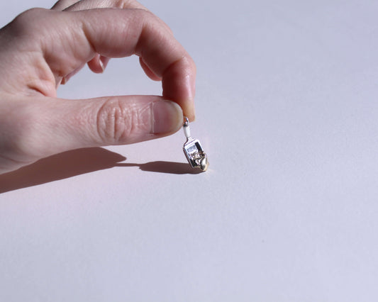 pendentif en argent symbolisant un poêlon à raclette avec du fromage qui coule