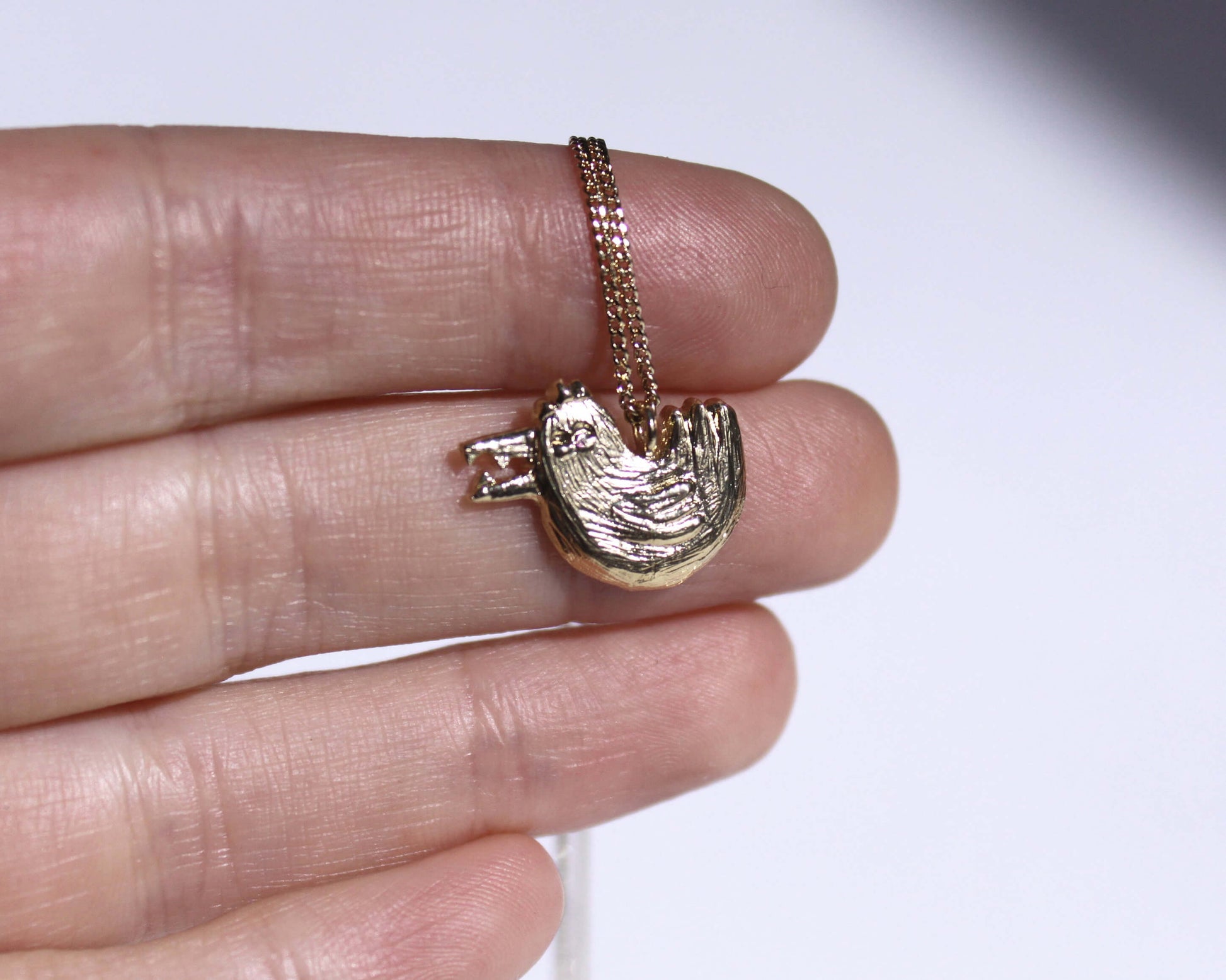 gros plan d'un pendentif en laiton plaqué or représentant une poule munie d'un bec avec des dents