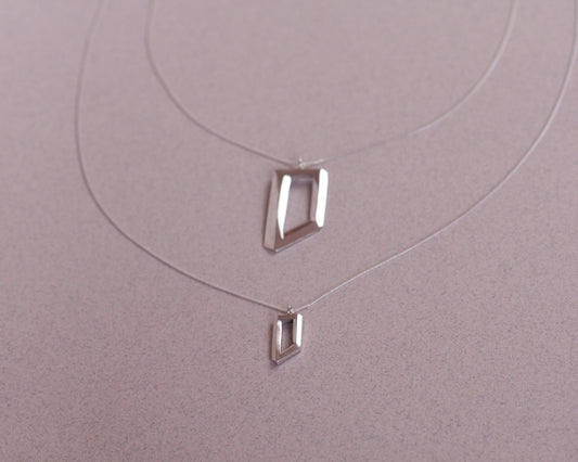 deux colliers avec des pendentifs en argent massif symbolisant des objets impossibles