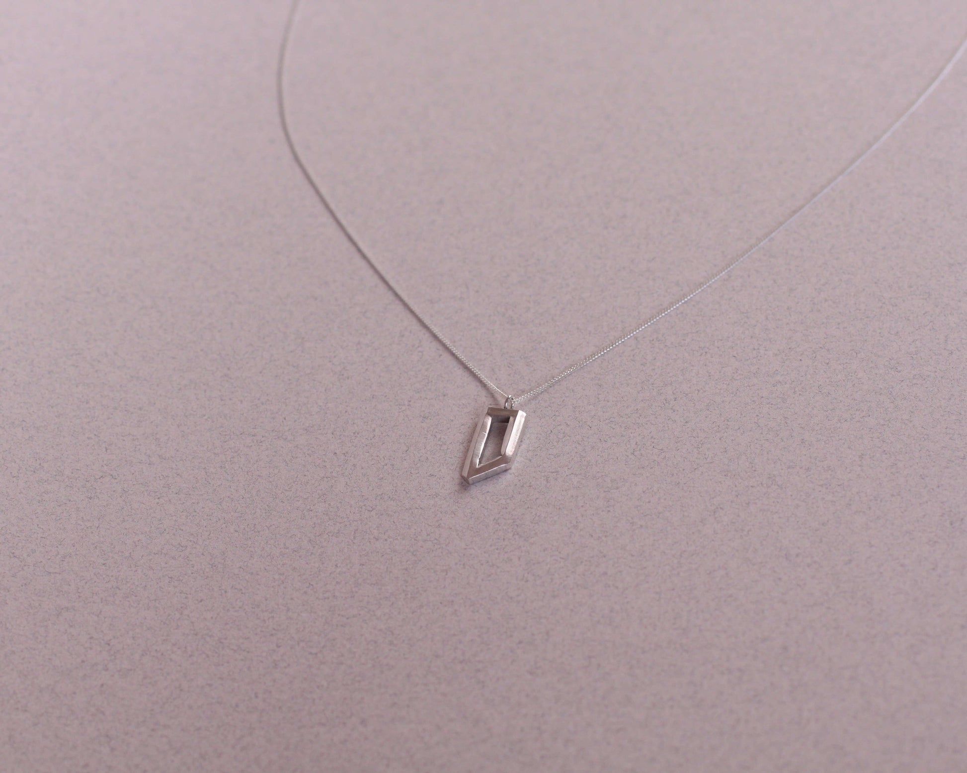 collier avec un pendentif en argent massif en forme d'objet impossible