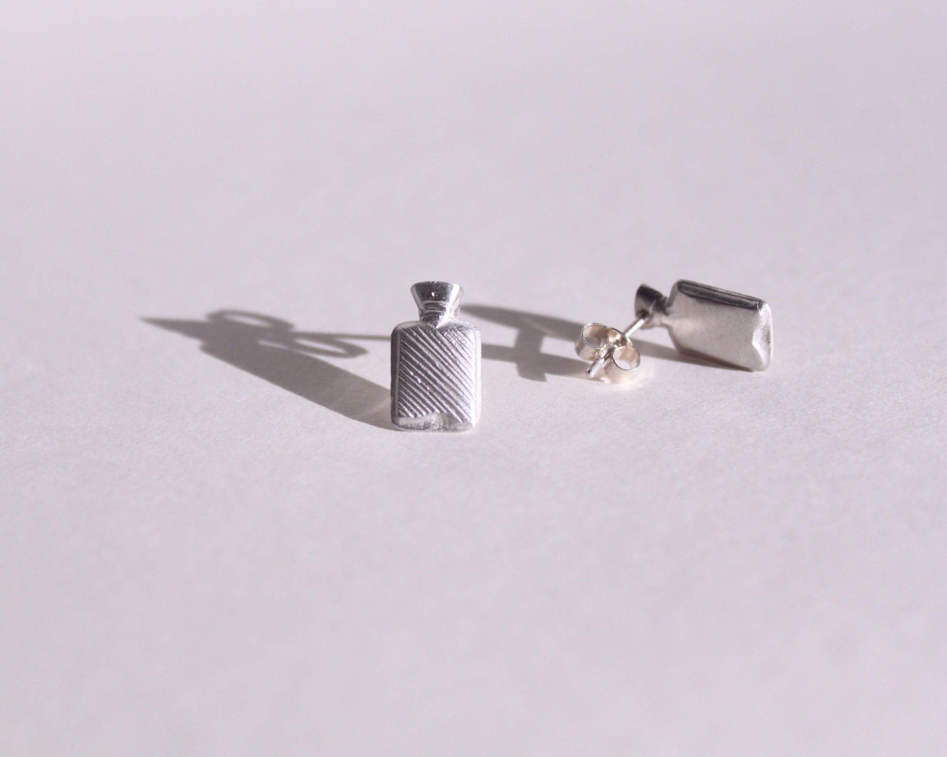 vue détaillée de puces d'oreilles en argent massif symbolisant des bouillottes