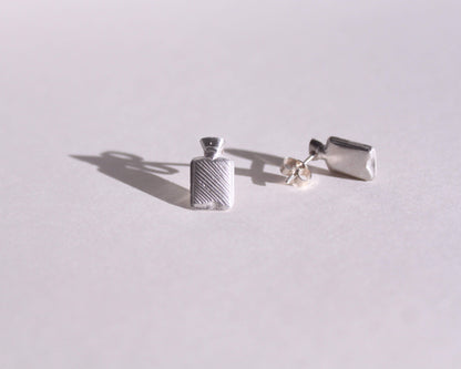 vue détaillée de puces d'oreilles en argent massif symbolisant des bouillottes